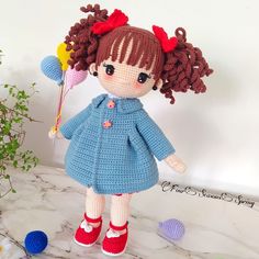 a crocheted doll is holding a flower in her hand and wearing red shoes