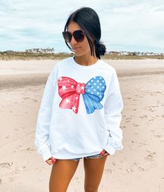 Get ready for summer and all your 4th of July activities in our cute and trendy American Bow Sweatshirt. We love this sweet sweatshirt paired with a skirt, as a beach coverup or tied over your shoulders on a cool summer evening.  A sturdy and warm sweatshirt bound to keep you warm in the colder months. A pre-shrunk, classic fit sweater that's made with air-jet spun yarn for a soft feel and reduced pilling. * 50% cotton, 50% polyester * Pre-shrunk * Classic fit * 1x1 athletic rib knit collar with Patriotic Long Sleeve Tops For Summer, Patriotic Long Sleeve Summer Tops, Cute Crew Neck T-shirt For Independence Day, White Crew Neck Sweatshirt For 4th Of July, Casual White Sweatshirt With American Flag Print, Patriotic White Cotton Sweatshirt, White Long Sleeve Tops For Independence Day, White Long Sleeve T-shirt For 4th Of July, White Long Sleeve T-shirt With American Flag Print