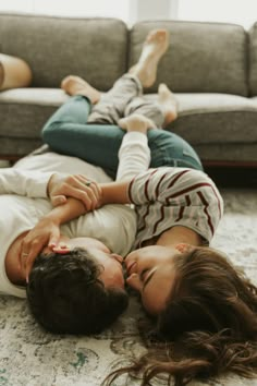 a man and woman laying on the floor in front of a couch