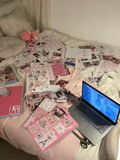 an open laptop computer sitting on top of a bed covered in pink and white stickers