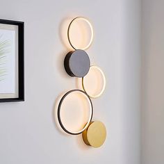 three circular lights mounted on the wall next to a framed photograph and plant in a black frame