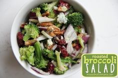 a white bowl filled with broccoli, cranberries and other food items