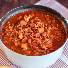 a large pot filled with chili and meat on top of a checkered table cloth