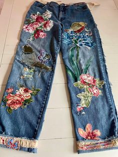 an old pair of jeans with flowers and birds painted on them are laying on the floor