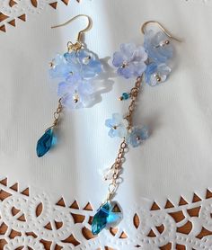 blue Sakura Flower Earrings The blue sakura flower earrings feature three glazed sakura and one crystal drop. They are really comfortable for everyday wear.  Available in GOLD and Silver finish! M A T E R I A L S * A N D * S I Z E  The hook is 14K gold filled - Length: 80mm(without the hook) - Width: 23mm Light Blue Flower Jewelry For Spring, Blue Flower-shaped Spring Jewelry, Bohemian Light Blue Flower Jewelry, Delicate Blue Flower Earrings With Ear Wire, Blue Dangle Earrings For Spring, Light Blue Jewelry For Spring Gift, Blue Whimsical Dangle Flower Earrings, Blue Flower-shaped Summer Earrings, Whimsical Blue Dangle Flower Earrings