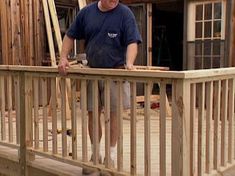 a man standing on top of a wooden deck next to a building under construction in the background