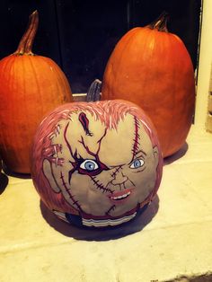 two pumpkins sitting on top of a counter next to each other with faces painted on them