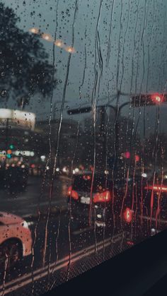 rain is falling on the window and cars are driving down the street in the distance