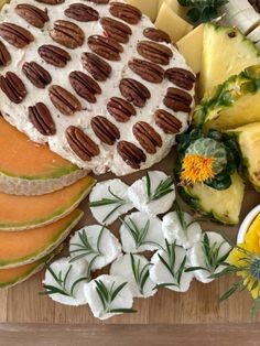 a wooden board topped with lots of different types of cheeses and fruit on top of it