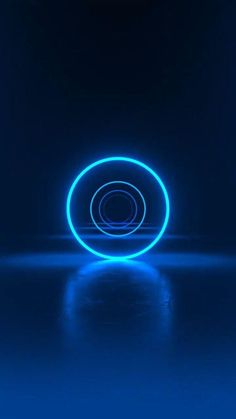 a neon blue circle on a dark background with reflections in the floor and light coming from it