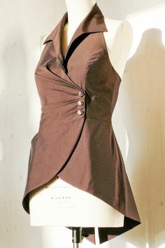 a mannequin wearing a brown shirt with buttons on the front and back, standing in front of a white wall