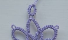 a crocheted purple flower is shown on a white surface