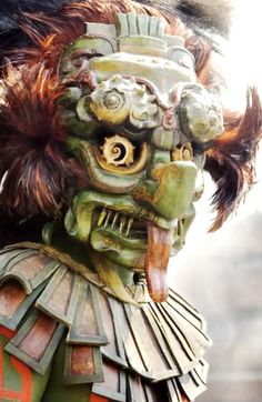 a close up of a person wearing an elaborate mask and headdress with feathers