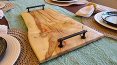 a wooden cutting board sitting on top of a table covered in plates and napkins