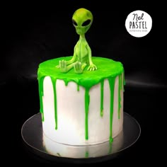 a green alien sitting on top of a white cake