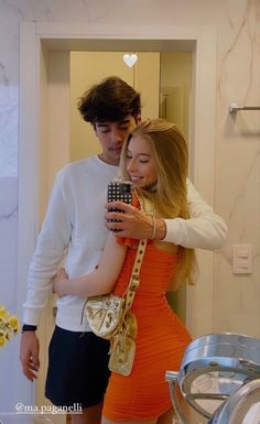 a man and woman taking a selfie in a bathroom mirror while holding a cell phone