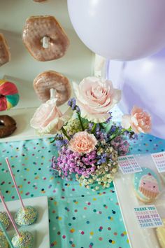 a table topped with lots of donuts and flowers