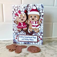 two gingerbreads are on top of a card