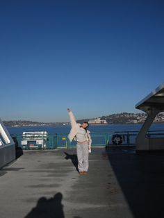 a person standing on a dock with their arms in the air and one hand up