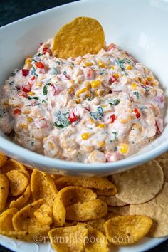 a white bowl filled with dip surrounded by chips