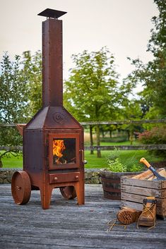 an outdoor wood burning stove in the middle of a wooden deck with logs and firewood