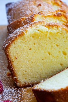 a loaf of pound cake sitting on top of a cutting board next to raspberries