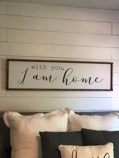 a bed with two pillows and a sign above it that says, with you i am home