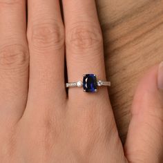 a woman's hand with a ring on it and a blue stone in the middle