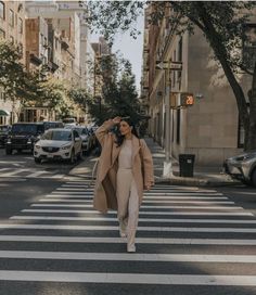 a woman walking across a cross walk in the street