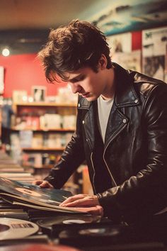 a man in a black leather jacket looking at records