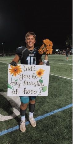 a young man holding a sign that says will you be my sunshine at once?