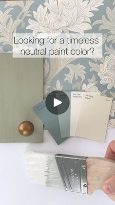 a person holding a paint brush next to some wallpaper and painting samples with the words looking for a timeless neutral paint color?