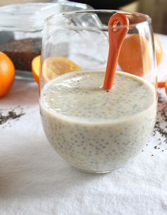 an orange and white drink sitting on top of a table next to sliced oranges