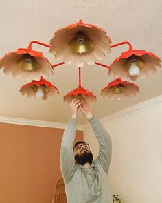 a man is reaching up to the ceiling with five lights on each side of his head