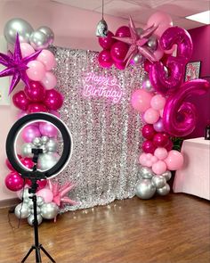 pink and silver balloons are on display in front of a backdrop