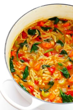 a white pot filled with pasta and vegetables