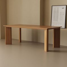 a wooden table sitting on top of a white floor next to a framed picture and window