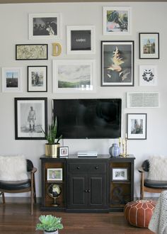 a living room with pictures on the wall and a television mounted to the wall above it