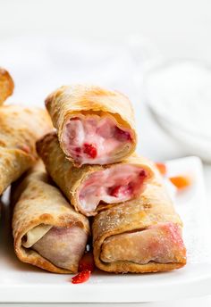 several pastries stacked on top of each other on a white plate with red sauce