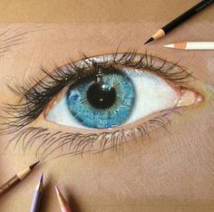 a drawing of an eye with colored pencils next to it and the eyes are blue