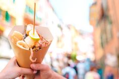 a person holding an ice cream sundae with bananas and other toppings in it