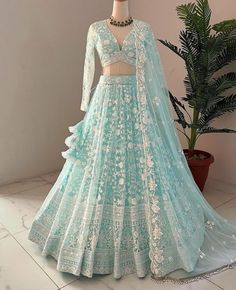 a light blue lehenga with white flowers on the skirt and cropped sleeves