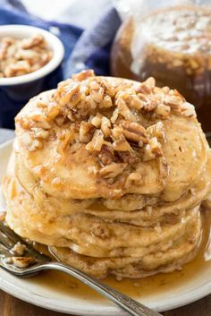 stack of pancakes topped with pecans and syrup