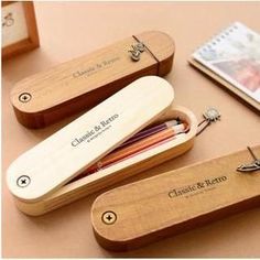 three wooden pencils are sitting next to each other on a table with a notepad