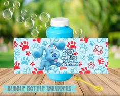 a blue bottle with an elephant on it and bubbles coming out of the top, sitting on a wooden table