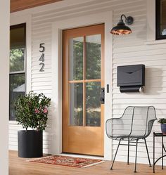 a chair sitting on top of a wooden floor next to a white house with a brown door