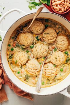 a pot filled with chicken and dumplings on top of a white table next to other food