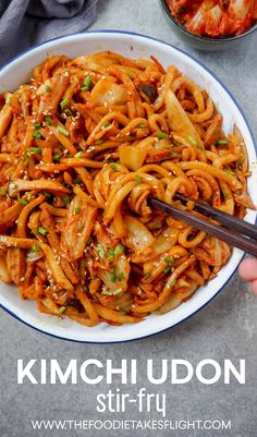 someone is holding chopsticks over a bowl of kimchi udon stir fry