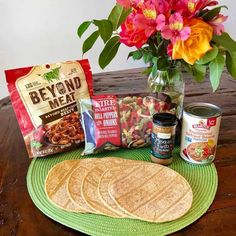 tortillas and other ingredients on a green place mat with flowers in the background