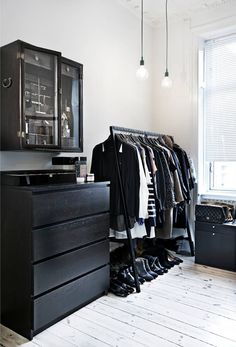 an organized closet with clothes and shoes hanging on the rack, in front of a window